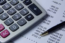 This is a picture of a calculator with some balance sheets in the background.